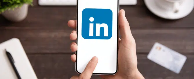 person sitting at a trendy desk using linkedin on a smartphone
