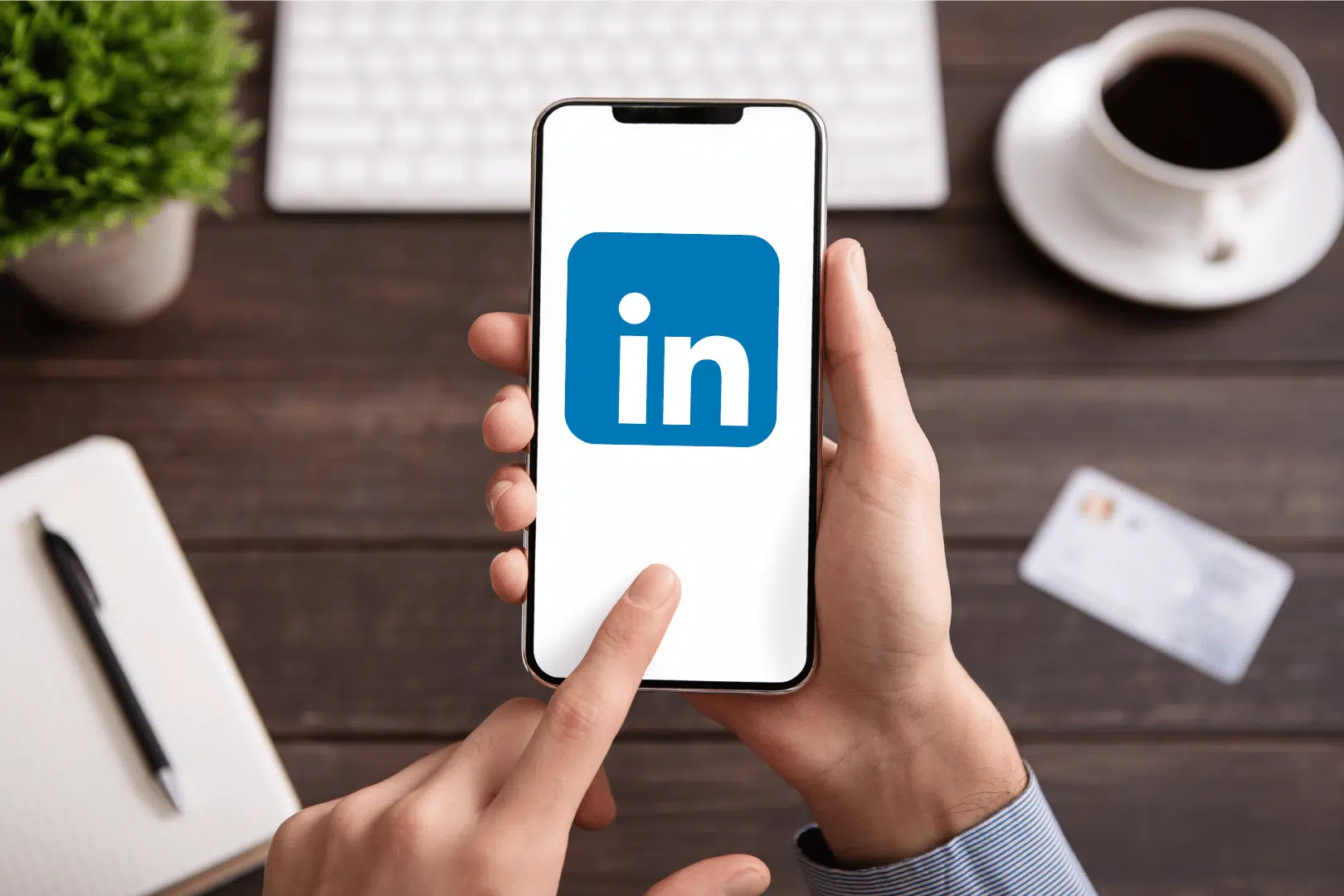 person sitting at a trendy desk using linkedin on a smartphone