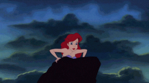 The Little Mermaid on a rock with a wave crashing in the background